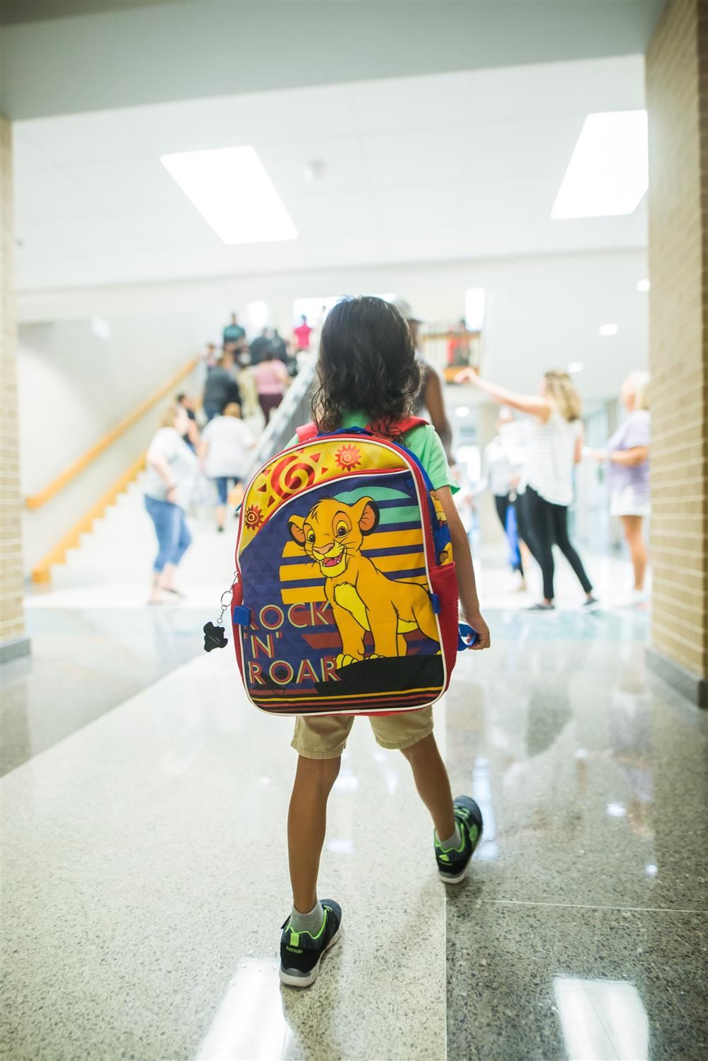  boy with lion king backpack walking into school 